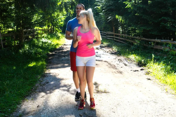 Correre coppia di corridori di fitness facendo sport su strada all'aperto. Vita attiva uomo e donna jogging formazione cardio in estate all'aperto natura . — Foto Stock