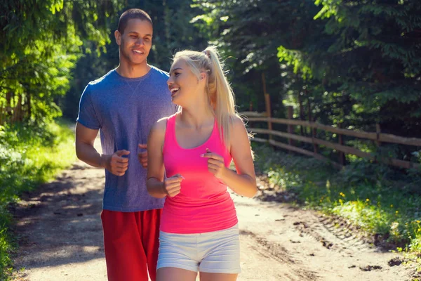 Running fitness couple of runners doing sport on road outdoor. Active living man and woman jogging training cardio in summer outdoors nature.