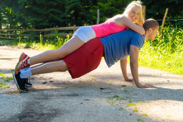 Joven pareja de deportes haciendo ejercicios en el bosque — Foto de Stock