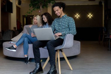 Üniversite öğrencileri, kitaplar ve dizüstü bilgisayarlarla aynı masada oturuyorlar. Üniversite kütüphanesinde bir grup çok ırklı insan..