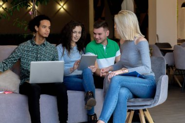 Üniversite öğrencileri, kitaplar ve dizüstü bilgisayarlarla aynı masada oturuyorlar. Üniversite kütüphanesinde bir grup çok ırklı insan..