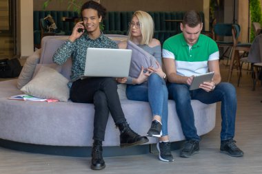 Üniversite öğrencileri, kitaplar ve dizüstü bilgisayarlarla aynı masada oturuyorlar. Üniversite kütüphanesinde bir grup çok ırklı insan..