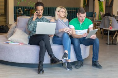 Üniversite öğrencileri, kitaplar ve dizüstü bilgisayarlarla aynı masada oturuyorlar. Üniversite kütüphanesinde bir grup çok ırklı insan..