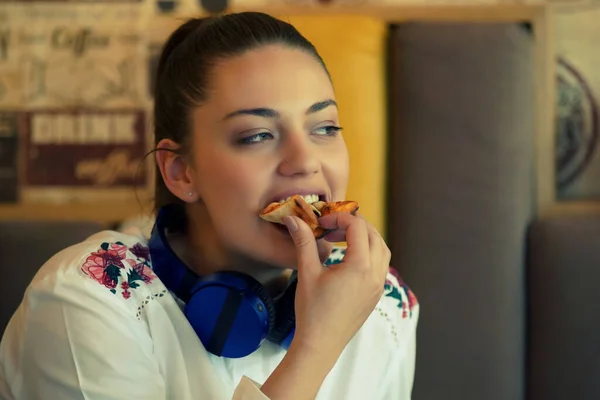 Bild einer glücklichen Frau, die im Café sitzt, Musik hört und Pizza isst — Stockfoto