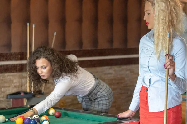 Beautiful smiling women playing billiards at a bar