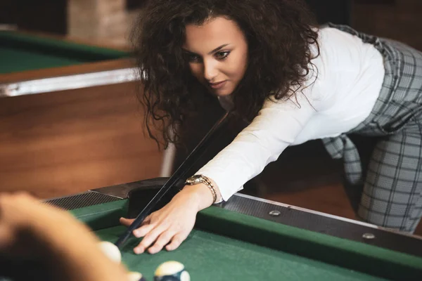 Beautiful smiling women playing billiards at a bar