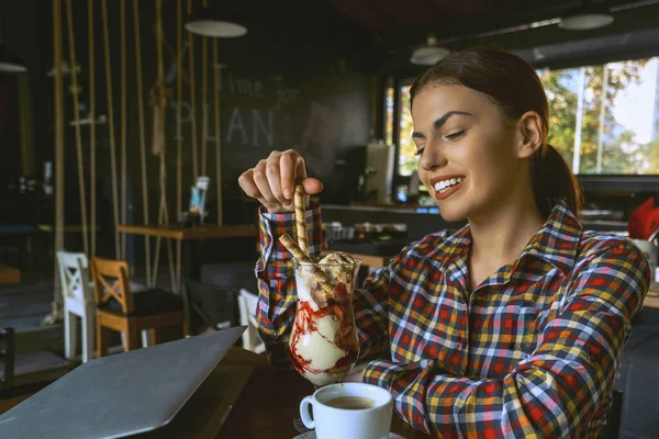 Ελκυστική ευτυχισμένη νεαρή γυναίκα κάθεται και τρώει το επιδόρπιο στο καφέ — Φωτογραφία Αρχείου