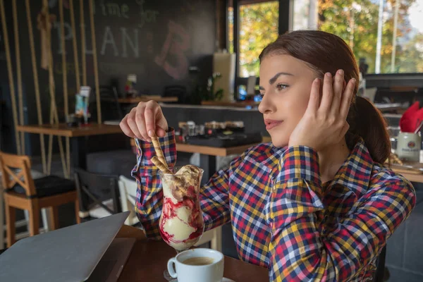 Ελκυστική ευτυχισμένη νεαρή γυναίκα κάθεται και τρώει το επιδόρπιο στο καφέ — Φωτογραφία Αρχείου
