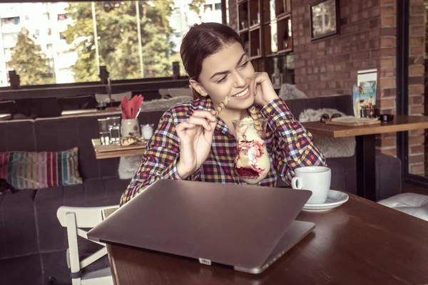 Atractiva joven feliz sentada y comiendo postre en la cafetería — Foto de Stock
