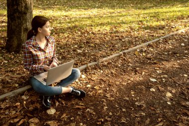 Güzel bir iş kadını, dizüstü bilgisayarlı, telefonla konuşan ve kredi kartı tutan.