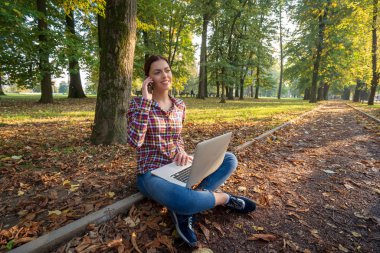 Güzel bir iş kadını, dizüstü bilgisayarlı, telefonla konuşan ve kredi kartı tutan.