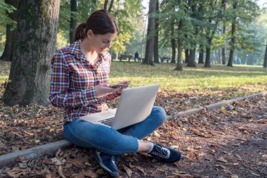 Güzel bir iş kadını, dizüstü bilgisayarlı, telefonla konuşan ve kredi kartı tutan.
