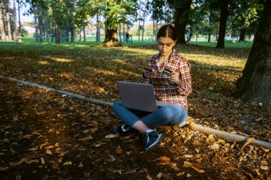 Güzel bir iş kadını, dizüstü bilgisayarlı, telefonla konuşan ve kredi kartı tutan.