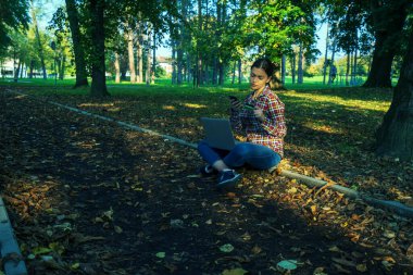 Güzel bir iş kadını, dizüstü bilgisayarlı, telefonla konuşan ve kredi kartı tutan.