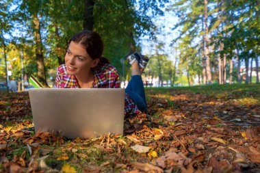 Parkta dizüstü bilgisayar ve banka kartı kullanan mutlu kadınlar. İnternetten alışveriş.