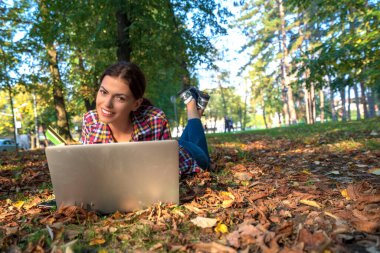 Parkta dizüstü bilgisayar ve banka kartı kullanan mutlu kadınlar. İnternetten alışveriş.