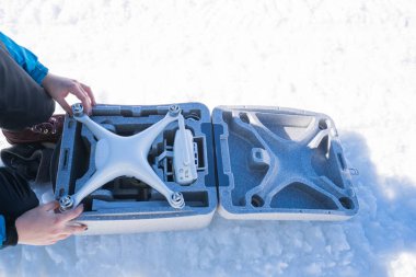 Kışın karlı ormanda uçan İHA genç bir kadın tarafından kullanılıyor.