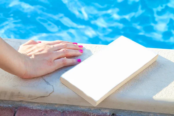 Mujer joven leyendo libro en la piscina — Foto de Stock