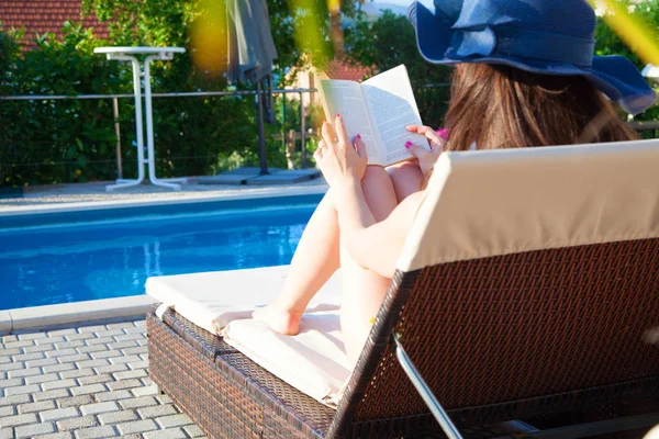 Jovencita leyendo libro cerca de la piscina — Foto de Stock