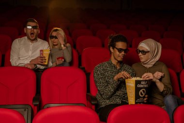 Gülen arkadaşların sinemada oturup film izlediği patlamış mısır yediği ve havalandırılmış tatlı su içtiği görüntüler..