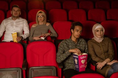 Gülen arkadaşların sinemada oturup film izlediği patlamış mısır yediği ve havalandırılmış tatlı su içtiği görüntüler..