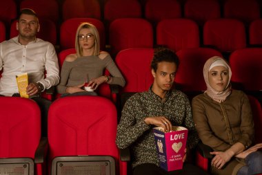 Gülen arkadaşların sinemada oturup film izlediği patlamış mısır yediği ve havalandırılmış tatlı su içtiği görüntüler..