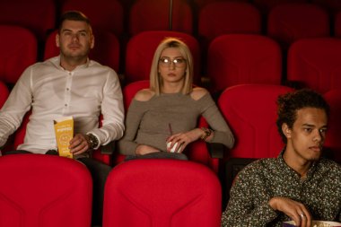 Gülen arkadaşların sinemada oturup film izlediği patlamış mısır yediği ve havalandırılmış tatlı su içtiği görüntüler..