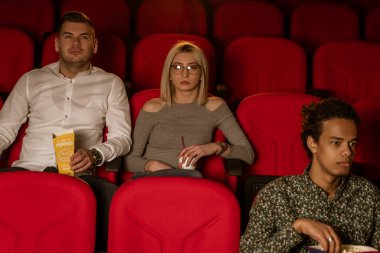 Gülen arkadaşların sinemada oturup film izlediği patlamış mısır yediği ve havalandırılmış tatlı su içtiği görüntüler..