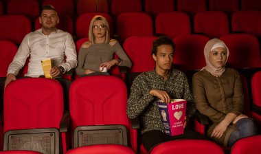 Gülen arkadaşların sinemada oturup film izlediği patlamış mısır yediği ve havalandırılmış tatlı su içtiği görüntüler..