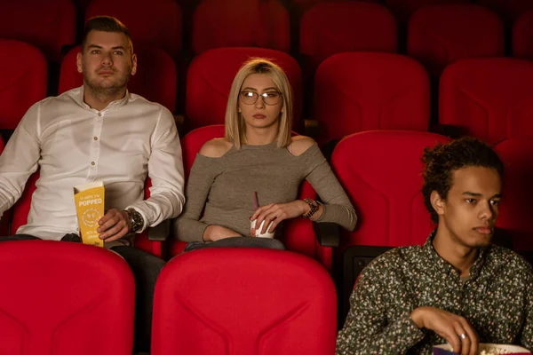 Gülen arkadaşların sinemada oturup film izlediği patlamış mısır yediği ve havalandırılmış tatlı su içtiği görüntüler..