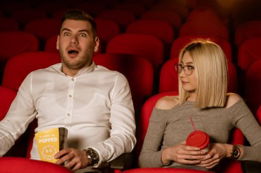 Sinemada genç bir çift film izliyor, patlamış mısır yiyor, gülümsüyor..