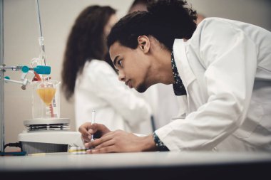 Laboratuvarda deney tüpüyle çalışan çok kültürlü bilim adamları.