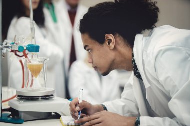 Laboratuvarda deney tüpüyle çalışan çok kültürlü bilim adamları.
