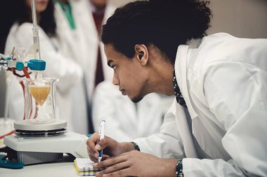 Laboratuvarda deney tüpüyle çalışan çok kültürlü bilim adamları.