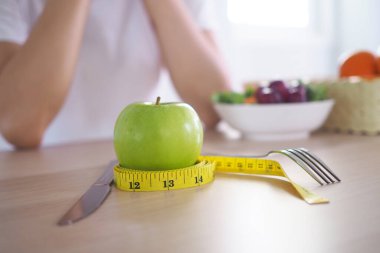 Yeşil elmanın etrafındaki şerit ölçü. Sonra tahta masada süt ve sebze salatası var. Sağlıklı beslenmek ve kilo vermek için. Diyet kavramı