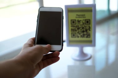 Eller, satın almada indirim almak için QR kodlarını taramak için telefonu kullanır..