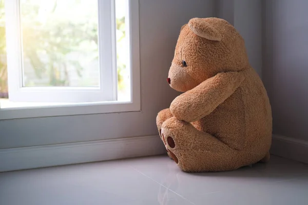 major depressive disorder mdd concept. Grief of children. Teddy bear sitting looking at the house window alone. Looks like someone who is sad, disappointed, depressed