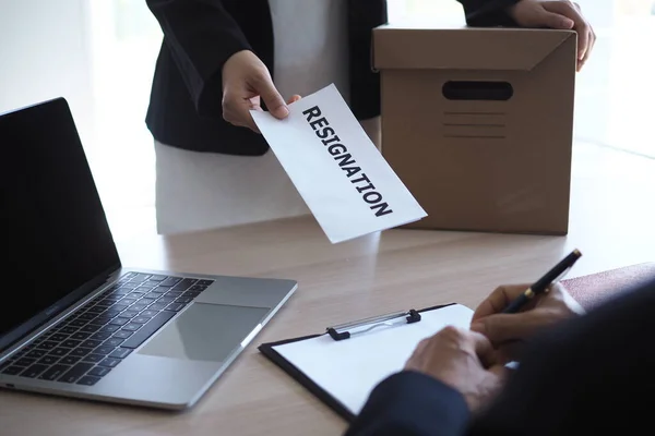 A female businessman holding a brown cardboard box and sends a resignation letter to the management