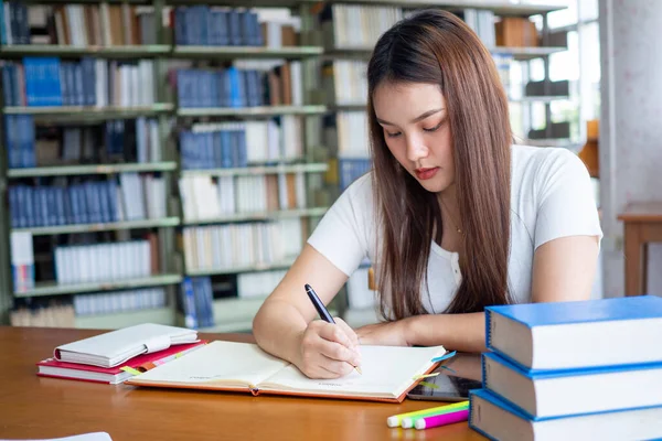 Güzel Asyalı kız öğrenciler ödevlerini yapıp kütüphanede rapor veriyorlar..