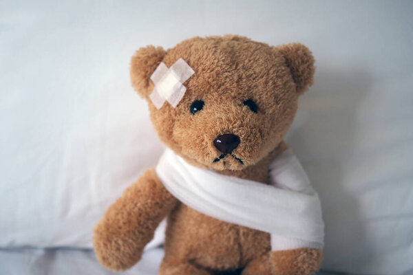 Грустная медведица лежит больная в постели с раной на голове и бинтом