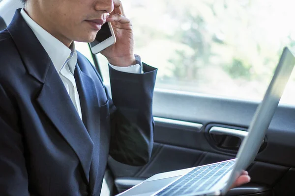 Business people talk on the phone and search for information on a laptop while traveling to negotiate off-site business.