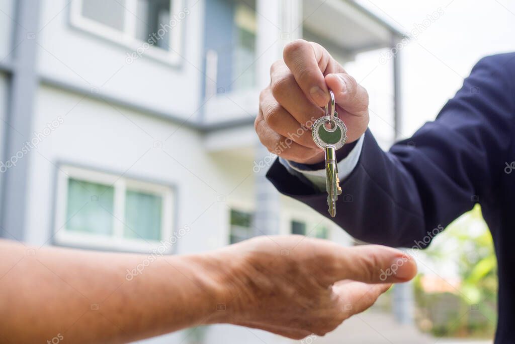 Agent sells the house shake hand with the buyer and send house key to the buyer.Sell house concept.