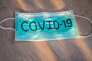 Maske Covid-19 'u doğal ışıkla yazmış. 2019-NCoV virüs enfeksiyonu tüm dünyaya yayılıyor. Ölümcül bir salgın. Konsept, koronavirüsü korumak için maske takar.