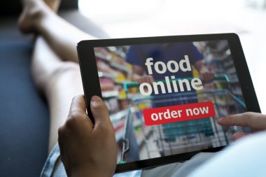 Kadınlar evdeki kanepede yatarken internetten yemek sipariş etmek için tablet kullanıyorlar..