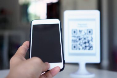 Eller, satın almada indirim almak için QR kodlarını taramak için telefonu kullanır..