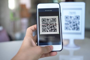 Kadınların eli QR kodlarını taramak için cep telefonu uygulaması kullanıyor. Mağazalarda para ve plastik etiketler olmadan dijital ödeme kabul ediyorlar. QR kod ödemesi ve nakit teknolojisi kavramı