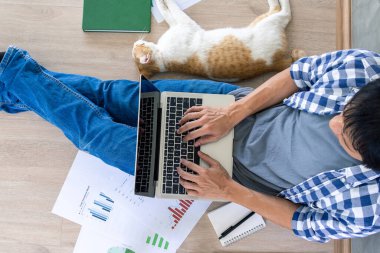 Adam evde evcil bir hayvanla yerde oturuyor. Not defterlerine basılmış belgelerle evde çalışmak. Konsept iş evden ve sosyal uzaklıktan.