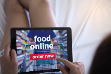 Kadınlar evdeki kanepede yatarken internetten yemek sipariş etmek için tablet kullanıyorlar..