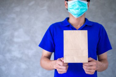 Kurye bir yemek çantası taşır ve maske takar. Müşterinin siparişi üzerine hızlı teslimat ve ücretsiz teslimat için internetten yemek dağıtmaya hazırdır. Çevrimiçi alışveriş ve hızlı teslimat