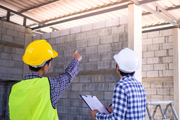 Mühendisler ya da mimarlar, müşterileri ya da müteahhitleri evin çatısının yapısını düzeltmenin detaylarını tartışıyorlar. Kaliteli işler için denetleme ve danışmanlık.